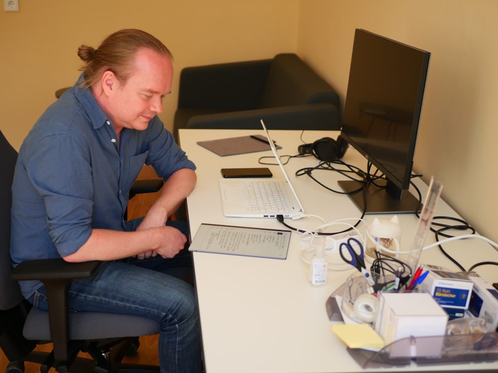 Markus Pantsar sitting at his desk reading in his notebook