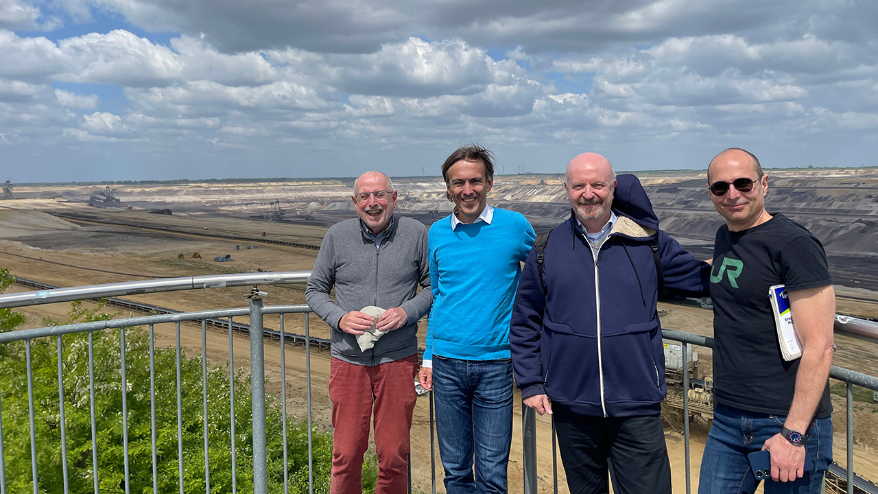 Four people posing outdoors with constaction fields in the background.