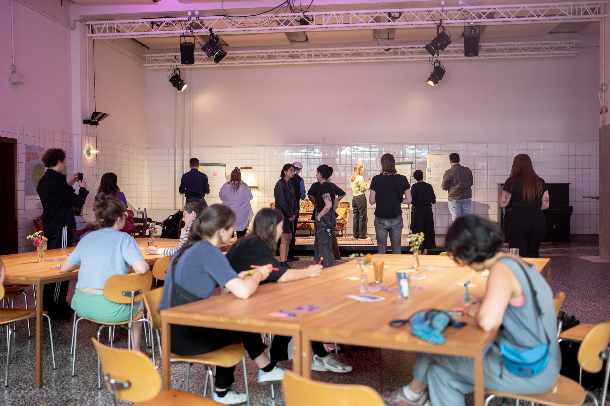 Many people are standing or sitting in small groups, talking in a large room.