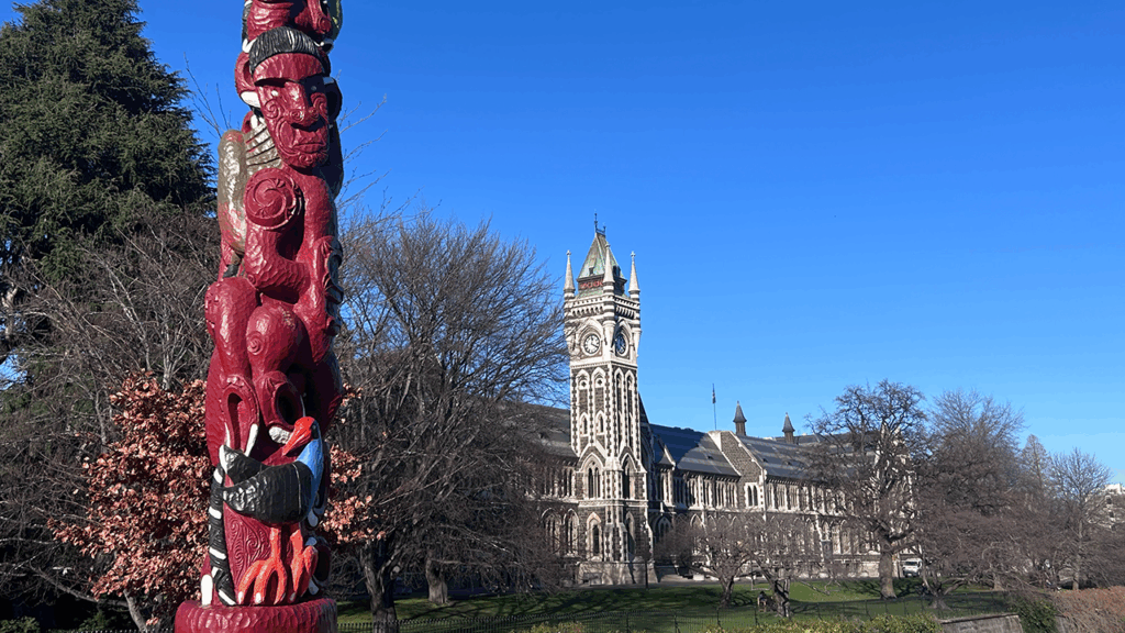 A red, tall sculpture in front of the building of the main building of the University of Otago in Dunedin, New Zealand.